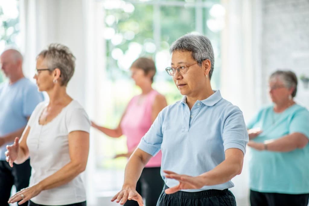 Older adults practicing Tai Chi movements in a bright indoor studio