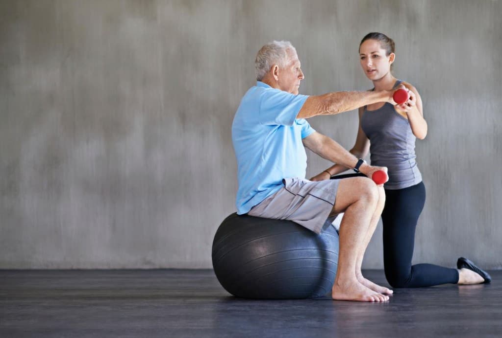 Instructor guiding an older adult through a safe balance exercise with professional support