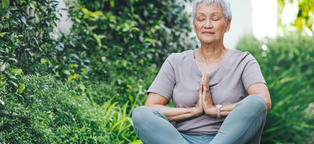 Older adult meditating outdoors in a garden setting