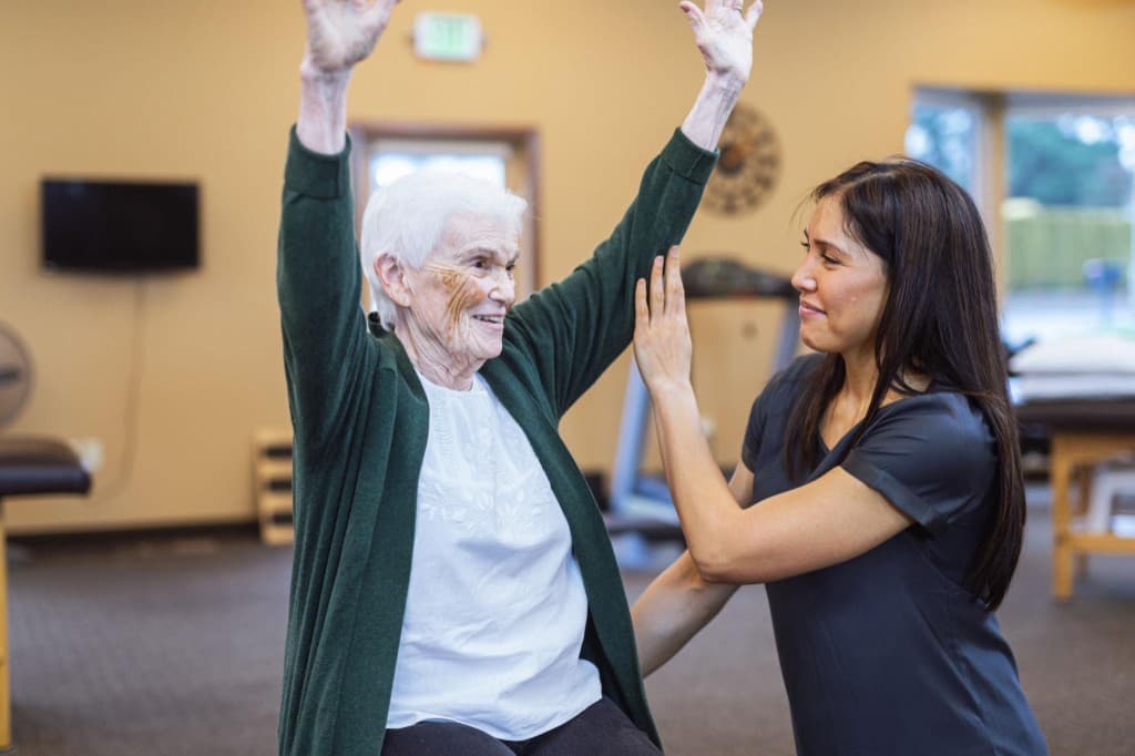 Therapist assisting a senior with a guided mobility exercise